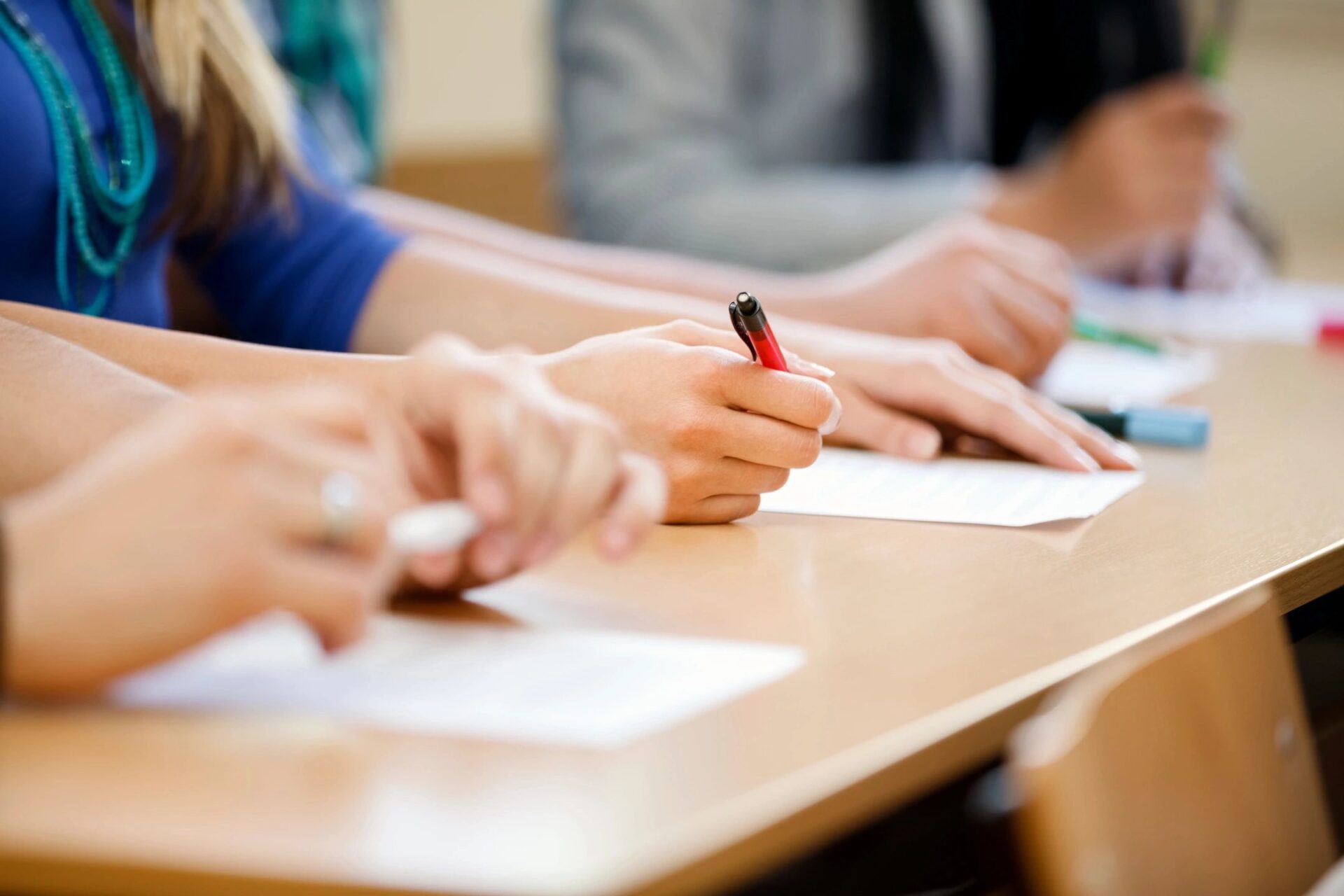 picture focusing on students hands in classroom as they take exam 