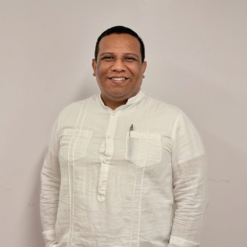 Smiling man in white shirt against wall